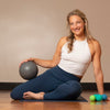 Woman sitting on a yoga mat with exercise balls in a home setting